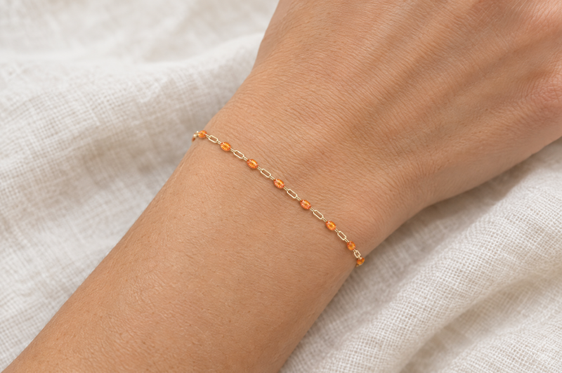 Load image into Gallery viewer, Harvest 14K gold filled paperclip chain with orange enamel stations, worn as a welded permanent bracelet
