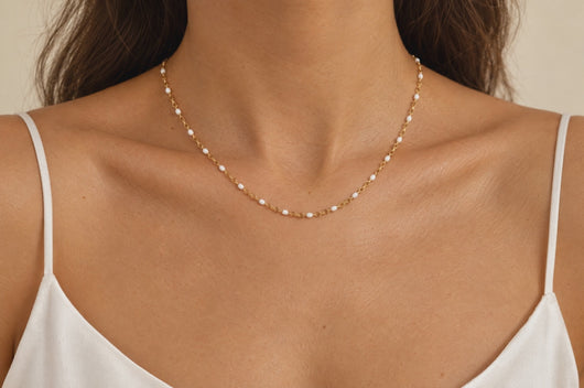 Snow gold and white enamel chain worn as a permanent necklace, model touching the chain
