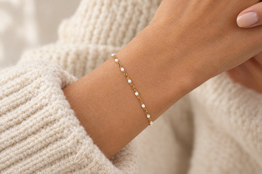 Snow 1.6mm gold PVD stainless steel chain with white enamel beads worn as a welded permanent bracelet